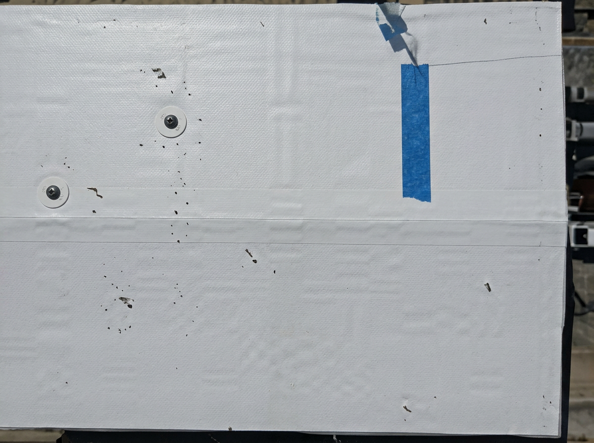 Close-up of a white TPO membrane commercial roof seam with fasteners and blue tape marker