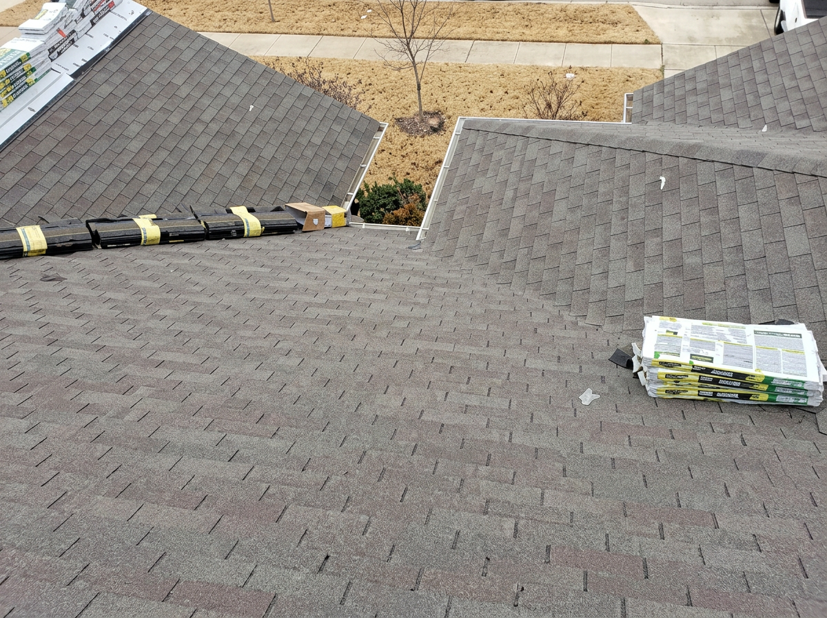 Overhead view of a residential roof with new architectural shingles and staged bundles